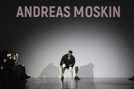 A Ukrainian war veteran puts on his prosthetic to take to the runway to demonstrate outfit by designers Andreas Moskin and Andriy Bilous during Fashion Week show in Kyiv, Ukraine, Tuesday, Sept. 3, 2024. (AP Photo/Efrem Lukatsky)
