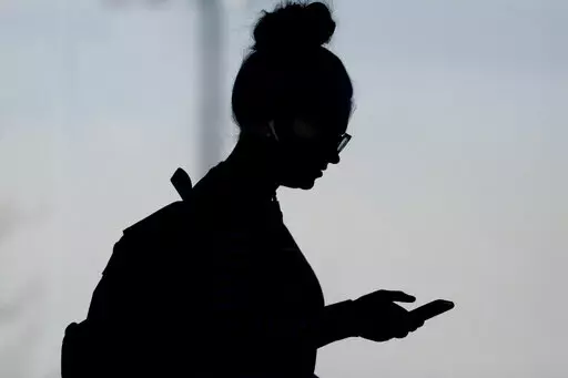 A woman checks her phone in Orem, Utah, on Nov. 14, 2019. A survey of people ages 16 to 40 finds that millennials and Generation Z follow the news, but they aren't that happy with what they're seeing. The study conducted by The Associated Press-NORC Center for Public Affairs Research and the American Press Institute says 79% of people follow news daily, contrary to perceptions that many are tuned out. (AP Photo/Rick Bowmer, File)
