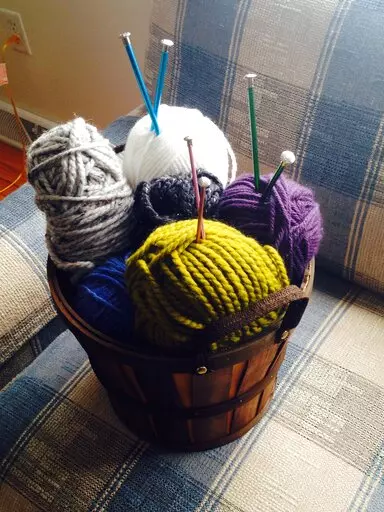 A basket of yarn rests on a couch in Middleborough, Mass. on Sept. 7, 2015. Many people have leaned into crafting, from knitting to beading to adult coloring books, during the pandemic. (AP Photo/Carolyn Lessard)