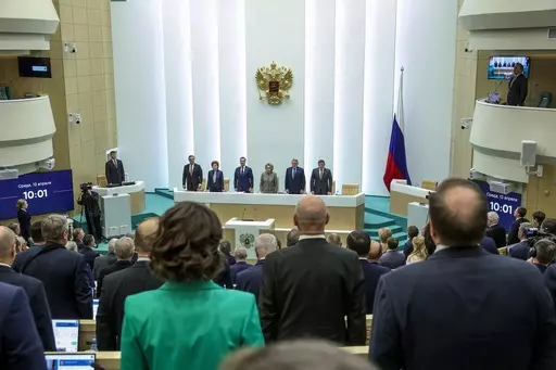 In this handout photo released by The Federal Assembly of The Russian Federation, members of the Federal Assembly of The Russian Federation listen to the national anthem as they attend a session in Moscow, Russia, Wednesday, April 12, 2023. The upper house of Russian parliament has swiftly approved a bill that would allow authorities to issue electronic summons to draftees and reservists amid the fighting in Ukraine. (The Federal Assembly of The Russian Federation via AP)