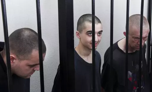 Two British citizens Aiden Aslin, left, and Shaun Pinner, right, and Moroccan Saaudun Brahim, center, sit behind bars in a courtroom in Donetsk, in the territory which is under the Government of the Donetsk People's Republic control, eastern Ukraine, Thursday, June 9, 2022. The two British citizens and a Moroccan have been sentenced to death by pro-Moscow rebels in eastern Ukraine for fighting on Ukraine's side. The three men fought alongside Ukrainian troops and surrendered to Russian forces we