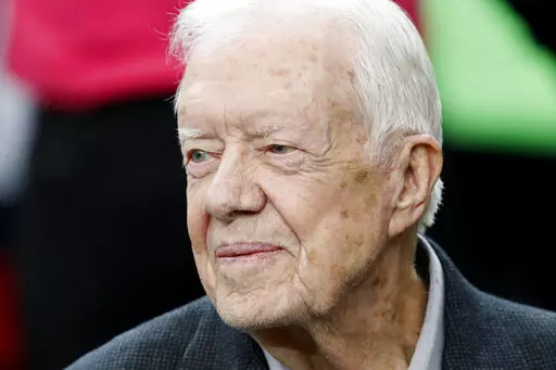 Former President Jimmy Carter sits on the Atlanta Falcons bench before the first half of an NFL football game between the Atlanta Falcons and the San Diego Chargers, Oct. 23, 2016, in Atlanta. Carter has entered home hospice care after a series of short hospital stays. The Carter Center said in a statement Saturday, Feb. 18, 2023, that Carter, 98, “decided to spend his remaining time at home with his family and receive hospice care instead of additional medical intervention.” (AP Photo/John 
