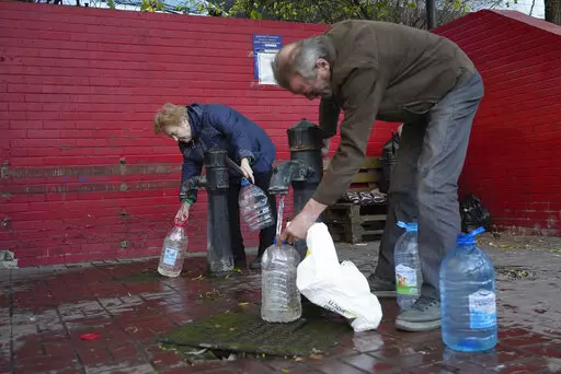People fill containers with water from public water pumps in Kyiv, Ukraine, Monday, Oct. 31, 2022. A massive barrage of Russian cruise missile and drone strikes hit critical infrastructure in Kyiv, Kharkiv and other Ukrainian cities on Monday morning, knocking out water and power supplies in apparent retaliation for what Moscow alleged was a Ukrainian attack on its Black Sea Fleet. (AP Photo/Sam Mednick)