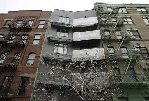 A new building sits between two older-style buildings in the East Harlem section of New York, Feb. 3, 2015. Legislation backed by a majority of the New York City Council would require landlords who hire brokers to pay their broker fees, marking a potential sea change in one of the country’s most expensive housing markets. (AP Photo/Seth Wenig, File)