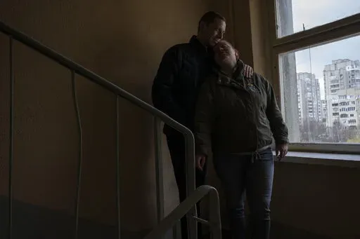 Iryna and Volodymyr, internally displaced from Irpin, lean on each other, on the stairwell near an apartment they took refuge in with four other adults from Irpin, in Lviv, western Ukraine, Sunday, April 3, 2022. Iryna and her husband Volodymyr were trapped for days between Ukrainian and Russian forces and quickly learned to distinguish between incoming and outgoing fire. They took shelter in a basement and whenever the shelling eased, they climbed out to shout to their neighbors to see if they 