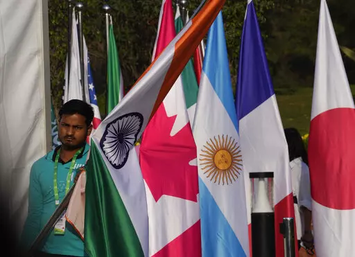 A worker carries Indian national flag to place it with those of other participating countries at the opening session of the G20 foreign ministers meeting, in New Delhi, India, Thursday, March 2, 2023. Top diplomats from the world’s major industrialized and developing nations on Thursday opened what are expected to be contentious talks dominated by Russia’s war in Ukraine and China’s moves to boost its global influence.(AP Photo/Manish Swarup)