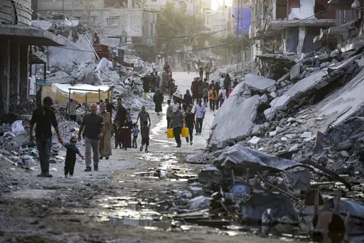 Palestinians displaced by the Israeli air and ground offensive on the Gaza Strip, walk through a dark streak of sewage flowing into the streets of the southern town of Khan Younis, Gaza Strip, on July 4, 2024. Health authorities and aid agencies are racing to avert an outbreak of polio in the Gaza Strip after the virus was detected in the territory's wastewater and three cases with a suspected polio symptom have been reported. (AP Photo/Jehad Alshrafi, File)