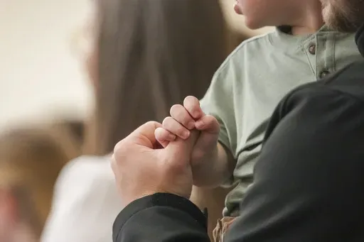 A child holds a man's finger during a service at Community Church of Seminole, Sunday, Feb. 23, 2025, in Seminole, Texas. (AP Photo/Julio Cortez)