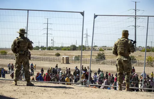 Migrants wait in line adjacent to the border fence under the watch of the Texas National Guard to enter into El Paso, Texas, Wednesday, May 10, 2023. U.S. authorities say an 8-year-old girl died Wednesday, May 17, in Border Patrol custody, a rare occurrence that comes as the agency struggles with overcrowding. The Border Patrol had 28,717 people in custody on May 10, the day before pandemic-related asylum restrictions expired, which was double from two weeks earlier, according to a court filing.
