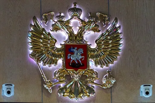 The emblem for the Russian Defense Ministry is displayed at the ministry building in Moscow, Russia on Monday, Sept. 26, 2016. On Saturday, Oct. 15, 2022, the ministry said two men fired at troops at a Russian military firing range near Ukraine, killing 11 and wounding 15 others, before getting killed. (AP Photo/Ivan Sekretarev, File)