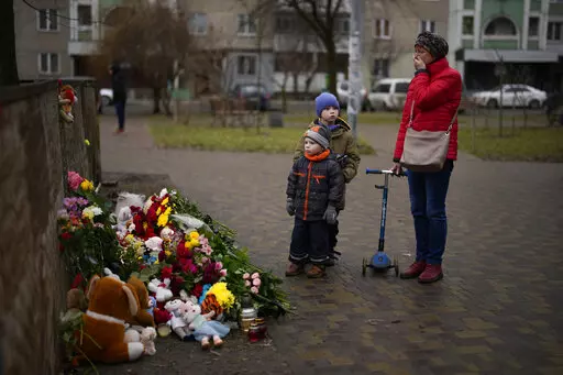 People pay their respects at a makeshift memorial at the scene where a helicopter crashed into civil infrastructure on Wednesday, Jan. 18, in Brovary, on the outskirts of Kyiv, Ukraine, Friday, Jan. 20, 2023. This past week has been an especially tragic one for Ukraine. A barrage of Russian missiles struck an apartment complex in the southeastern city of Dnipro on Jan. 14, and the death toll from that attack rose steadily in the days that followed, with at least 45 civilians killed, including si