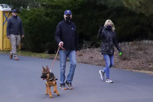 President Joe Biden and first lady Jill Biden take their dog Commander for a walk in Rehoboth Beach, Del., Tuesday, Dec. 28, 2021. (AP Photo/Patrick Semansky)