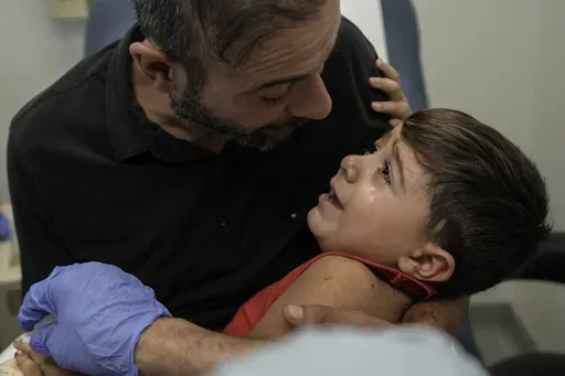 Hassan Mikdad, holds his son Hussein Mikdad, 4, who was injured on Oct. 2 in an Israeli airstrike at a densely-populated neighborhood south of Beirut, as he cries during a check up by his doctor at the American University of Beirut Medical Center (AUBMC), in Beirut, Lebanon, Tuesday, Nov. 5, 2024. (AP Photo/Bilal Hussein)