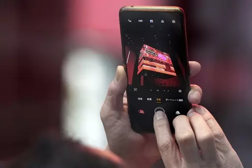 A person takes photograph an electronic stock board showing Japan's Nikkei 225 index at a securities firm Thursday, Feb. 22, 2024, in Tokyo. Japan’s benchmark Nikkei 225 index surged Thursday past the record it set in 1989 before its financial bubble burst, ushering in an era of faltering growth. (AP Photo/Eugene Hoshiko)