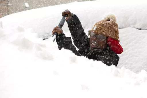 Zaria Black, 24, from Buffalo, clears off her car as snow falls Friday, Nov. 18, 2022, in Buffalo, N.Y.  A dangerous lake-effect snowstorm paralyzed parts of western and northern New York, with nearly 2 feet of snow already on the ground in some places and possibly much more on the way.  (AP Photo/Joshua Bessex)