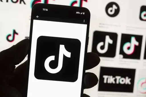 The TikTok logo is displayed on a mobile phone in front of a computer screen, Oct. 14, 2022, in Boston. TikTok will begin labeling content created using artificial intelligence when it's uploaded from certain platforms. TikTok says its efforts are an attempt to combat misinformation from being spread on its social media platform. The announcement came on ABC's “Good Morning America” on Thursday, May 9, 2024. (AP Photo/Michael Dwyer, File)