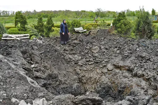 Orthodox Sister Evdokia gestures in front of the crater of an explosion, after Russian shelling next to the Orthodox Skete in honour of St. John of Shanghai in Adamivka, near Slovyansk, Donetsk region, Ukraine, Tuesday, May 10, 2022. (AP Photo/Andriy Andriyenko)