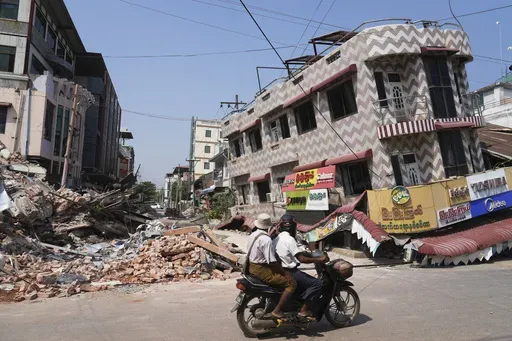 A local man drives a motorbike past damaged buildings in the aftermath of an earthquake in Naypyitaw, Myanmar, Sunday, March 30, 2025. (AP Photo/Aung Shine Oo)