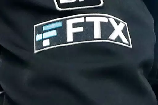 The FTX logo appears on home plate umpire Jansen Visconti's jacket at a baseball game with the Minnesota Twins on Sept. 27, 2022, in Minneapolis. The FTX bankruptcy filing followed a bruising of crypto companies throughout 2022, due in part to rising interest rates and the broader market downturn that has many investors rethinking their lust for risk. (AP Photo/Bruce Kluckhohn, File)
