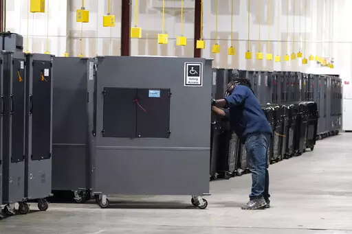 A worker returns voting machines to storage at the Fulton County Election preparation Center on Nov. 4, 2020 in Atlanta, Ga. The list of security breaches at local election offices since the 2020 election keeps growing, with investigations ongoing in at least three states, Colorado, Georgia and Michigan. Security experts say the breaches by themselves have not necessarily increased threats to the November elections, but say they increase the possibility that rogue election workers could access e