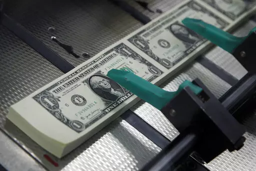 FILE- In this Nov. 15, 2017, file photo, new $1 bills with the signatures of U.S. Treasurer Jovita Carranza and Treasury Secretary Steven Mnuchin are cut and stacked at the Bureau of Engraving and Printing in Washington.  Want to quit your job? You’re not just walking away from a paycheck. If you’re not thoughtful with your exit strategy, you may leave money behind in less obvious places, like your commuter account or health savings plan.   (AP Photo/Jacquelyn Martin, File)