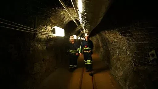 Two researchers walk through an old mining tunnel to what is now the Sanford Underground Research Facility in Lead, S.D., on Dec. 8, 2019. The laboratory houses a dark matter detector.  Scientists have begun a new search for mysterious dark matter in a former gold mine a mile underground. Dark matter makes up the vast majority of the mass of the universe but scientists don't know what it is. (AP Photo/Stephen Groves)