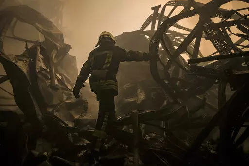 A Ukrainian firefighter walks inside a large food products storage facility which was destroyed by an airstrike in the early morning hours on the outskirts of Kyiv, Ukraine, Sunday, March 13, 2022. Waves of Russian missiles pounded a military training base close to Ukraine's western border with NATO member Poland, killing 35 people, following Russian threats to target foreign weapon shipments that are helping Ukrainian fighters defend their country against Russia's grinding invasion.(AP Photo/Va