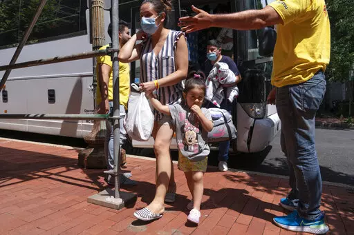 Silvia Moreno del Castillo, center, of Lima, Peru, holds her daughter Brisa, 3, by the hand, followed by her husband Gerardo Puente, as the family who is seeking asylum from Peru is greeted by Derick Alegria, left, and Orlando Andara, both with the nonprofit SAMU First Response, as a bus of asylum seekers who were sent from Arizona to Washington arrives, Thursday, Aug. 11, 2022, to a church on Capitol Hill in Washington. Moreno del Castillo had an allergic reaction on her feet and ankles while m