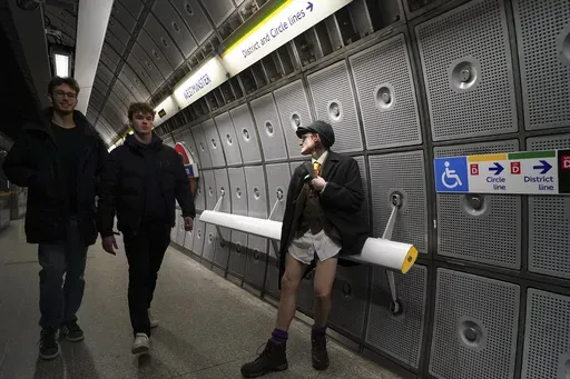 A man sits by the platform of an underground station, during the annual event "No Trousers Tube Ride" in London, Sunday, Jan. 12, 2025. (AP Photo/Alberto Pezzali)