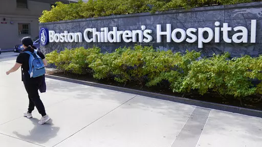 FILE — A woman walks past a sign outside the Boston Children's Hospital, Thursday, Aug. 18, 2022, in Boston. The American Academy of Pediatrics, the American Medical Association and the Children's Hospital Association are asking U.S. Attorney General Merrick Garland to investigate and prosecute people who are threatening violence against children's hospitals and physicians that provide gender-affirming health care. (AP Photo/Charles Krupa, File)
