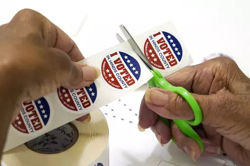 A precinct worker in Jackson, Miss., cuts individual "I Voted in Hinds County" stickers on Aug. 8, 2023. Election officials in Mississippi's most populous county had to scramble to complete required poll worker training after an early September breach involving county computers. (AP Photo/Rogelio V. Solis, File)