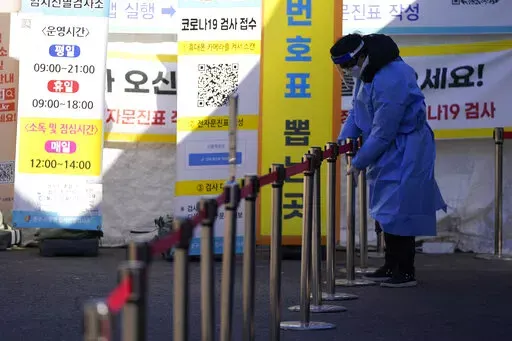 A health worker wearing protective gear prepares for visitors in the sub-zero temperatures at a temporary screening clinic for the coronavirus in Seoul, South Korea, Friday, Jan. 14, 2022. (AP Photo/Lee Jin-man)