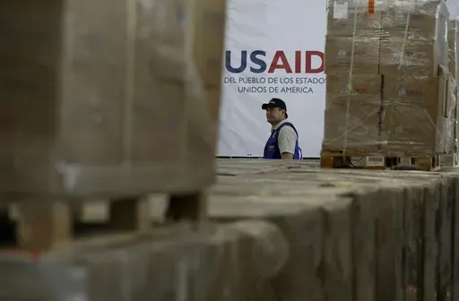 A man walks past boxes of USAID humanitarian aid at a warehouse at the Tienditas International Bridge on the outskirts of Cucuta, Colombia, Feb. 21, 2019, on the border with Venezuela. (AP Photo/Fernando Vergara)