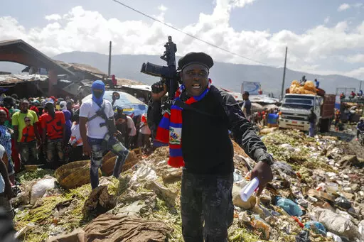 Barbecue, the leader of the "G9 and Family" gang, stands next to garbage to call attention to the conditions people live in as he leads a march against kidnapping through La Saline neighborhood in Port-au-Prince, Haiti, Friday, Oct. 22, 2021. Haiti Prime Minister Ariel Henry and 18 top-ranking officials have requested on the second week of Oct. 2022, the immediate deployment of foreign armed troops as gangs and protesters paralyze the country. (AP Photo/Odelyn Joseph, File)