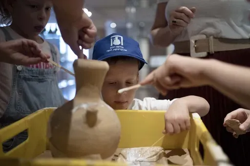 Ariel Heller, 4, helps to glue a broken clay jar during a special tour with his family after he accidentally broke another jar at the Reuben and Edith Hecht Museum in Haifa, Israel, Friday, Aug. 30, 2024. The boy who accidentally broke a rare 3,500-year-old jar in an Israeli museum has been forgiven and invited back, as curators hope to turn the disaster into a teachable moment. (AP Photo/Maya Alleruzzo)