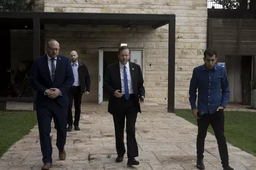 Israel's President Isaac Herzog, center, walks with his staff after an interview at his official residence in Jerusalem, Thursday, Dec. 14, 2023. (AP Photo/Maya Alleruzzo)