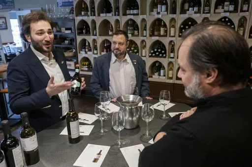Giorgi Iukuridze, owner and CEO Shabo, a Ukrainian winery, left, and Sam Lerman, CEO of SPYRT Worldwide, introduce Ukrainian wine to the owner of Wine Styles Arthur Lampros, right, at Wine Styles, Dec. 20, 2024 in Dumfries, Va. (AP Photo/Kevin Wolf)