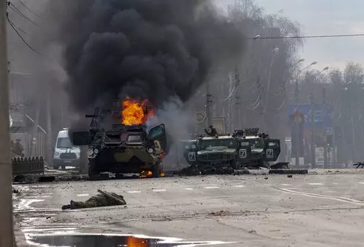 A Russian armored personnel carrier burns amid damaged and abandoned light utility vehicles after fighting in Kharkiv, the country's second-largest city in Ukraine, Feb. 27, 2022. Three months after it invaded Ukraine hoping to overtake the country in a blitz, Russia has bogged down in what increasingly looks like a war of attrition with no end in sight. (AP Photo/Marienko Andrew, File)