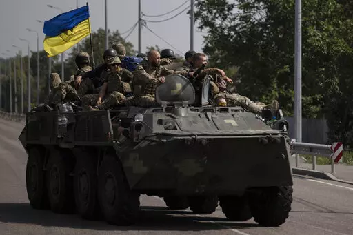 Ukrainian servicemen ride atop of an armored vehicle on a road in Donetsk region, eastern Ukraine, Sunday, Aug. 28, 2022. As the war slogs on, a growing flow of Western weapons over the summer is now playing a key role in the counteroffensive, helping Ukraine significantly boost its precision strike capability. (AP Photo/Leo Correa, File)