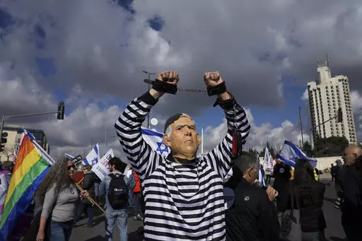 A protester wearing a rubber mask depicting Israeli Prime Minister Benjamin Netanyahu demonstrates in front of the Supreme Court in Jerusalem against the appointment of Aryeh Deri, the leader of the ultra-Orthodox Shas party as the country's new health minister, Thursday, Jan, 5, 2023. (AP Photo/Mahmoud Illean, File)