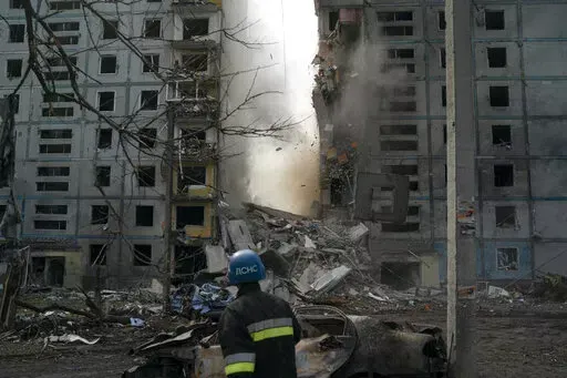 A firefighter looks at a part of a wall falling from the residential building that was heavily damaged after a Russian attack in Zaporizhzhia, Ukraine, Sunday, Oct. 9, 2022. (AP Photo/Leo Correa)