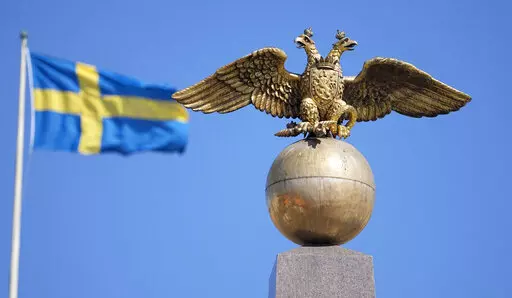 A Russian Imperial double-headed eagle is seen in front of a Swedish flag on the Czarina's Stone in the Market Square, in Helsinki, Finland, Friday, May 13, 2022. Finland and Sweden have signaled their intention to join NATO over Russia’s war in Ukraine and things will move fast once they formally apply for membership in the world’s biggest security alliance. Russian President Vladimir Putin has already made clear that there would be consequences if the two Nordic countries join. (AP Photo/M