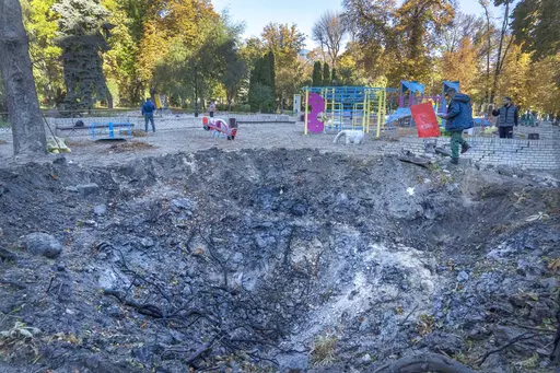 A man passes past a rocket crater at playground in city park in center Kyiv, Ukraine, Tuesday, Oct. 11, 2022.  On Friday, Oct. 14, The Associated Press reported on stories circulating online incorrectly claiming Ukrainian media is reporting that President Volodymyr Zelenskyy’s office was destroyed by a missile strike.  (AP Photo/Efrem Lukatsky)
