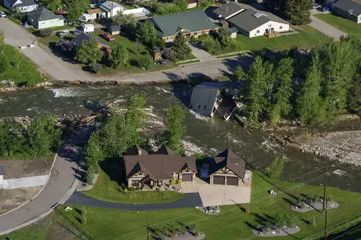 A house sits in Rock Creek after floodwaters washed away a road and a bridge in Red Lodge, Mont., in Red Lodge, Mont., June 16, 2022. (AP Photo/David Goldman, File)