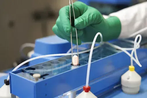 In this photo provided by Pfizer, a technician handles one of the company's COVID-19 Paxlovid pills. COVID-19 patients have two new treatment options that can be taken at home. But that convenience comes with a catch: The pills have to be taken as soon as possible once symptoms appear. U.S. regulators authorized the pills from Pfizer and Merck late 2021. (Pfizer via AP, File)
