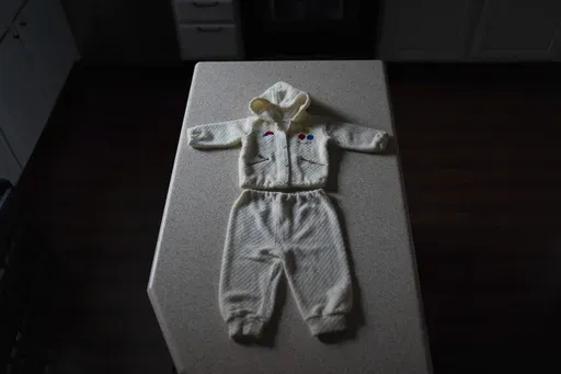 The outfit Leah Elmquist traveled in when she was adopted from Korea at five months old to a family in America, is arranged for a photograph at her home in Las Vegas on Monday, June 24, 2024. (AP Photo/David Goldman)