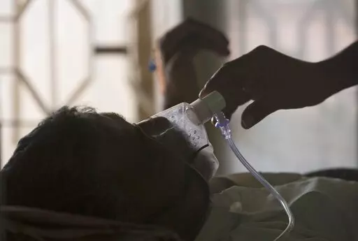 A relative adjusts the oxygen mask of a tuberculosis patient at a TB hospital on World Tuberculosis Day in Hyderabad, India, March 24, 2018. The number of people infected with tuberculosis, including the kind resistant to drugs, rose globally for the first time in years, according to a report issued Thursday, Oct. 27, 2022 by the World Health Organization. (AP Photo/Mahesh Kumar A., File)
