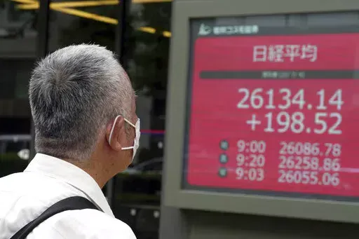 A person wearing a protective mask watches an electronic stock board showing Japan's Nikkei 225 index at a securities firm Monday, July 4, 2022, in Tokyo. Shares were mixed in Asia on Monday while U.S. futures fell ahead of the July 4 holiday in the U.S. (AP Photo/Eugene Hoshiko)