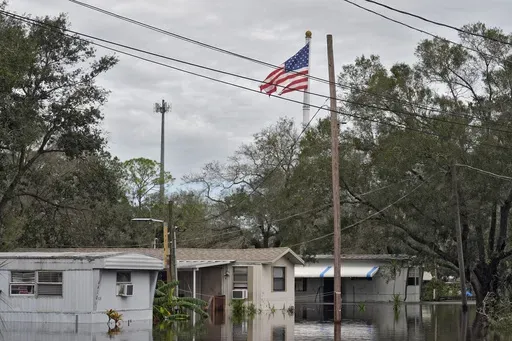 A tattered American flag flies above flooded homes, from Hurricane Milton along the Alafia river Friday, Oct. 11, 2024, in Lithia, Fla. (AP Photo/Chris O'Meara)