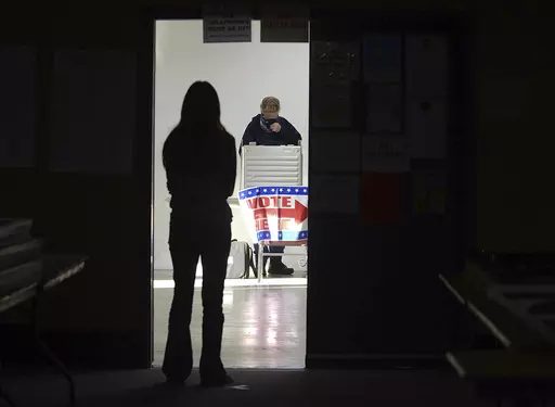 A first-time voter waits in the doorway for a voting booth as another voter completes his ballot at the Boot City Opry near Terre Haute, Ind., Nov. 3, 2020. (Joseph C. Garza/The Tribune-Star via AP, File)